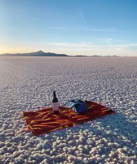A towel and a bottle of wine set up during sunset on the Uyuni Salt Flat.