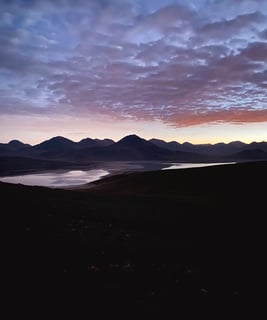 Sunrise during the ascent of Licancabur volcano, with warm light illuminating the rocky terrain.
