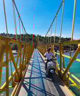 Photo of a local crossing the Yellow Bridge connecting Nusa Ceningan to Nusa Lembongan on a scooter.