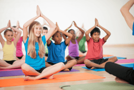 Children group yoga with rainbow colored mats