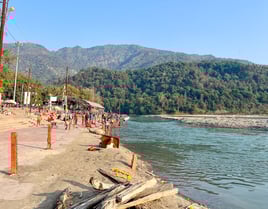 View of the sacred Ganges River flowing through Rishikesh, India, with the Himalayan mountains in the background.