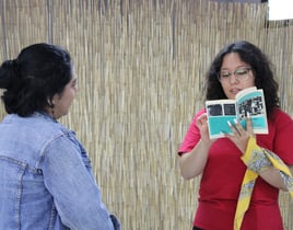 Una mujer leyéndole en voz alta a otra mujer