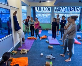 Yoga students practicing asanas together under the guidance of their teacher during a training session in Rishikesh, India.