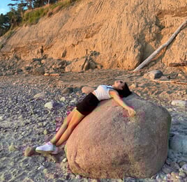 A picture of a woman laying on rock on a beach