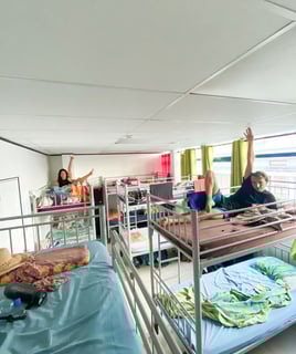 Dormitory room in a hostel in Tahiti with multiple beds and basic furnishings.