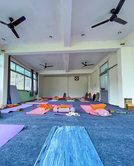 Yoga mats neatly arranged on the floor inside a bright and spacious training room, ready for a yoga class.