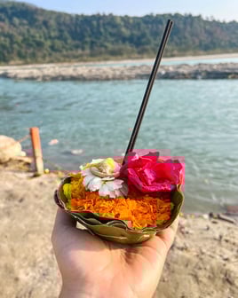 Close-up of flowers and incense sticks arranged as an offering during a ritual by the Ganges River.