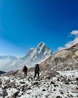Manon and her Nepali guide walking with the snow-covered peak of Taboche in the background.