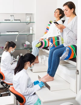 Two lady customers recieving pedicure services