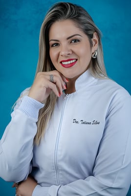 mulher loira médica com jaleco branco posando com a mão no queixo e sorrindo, posando em fundo azul
