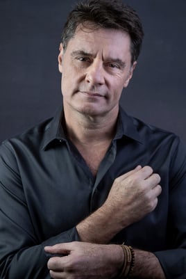 Ator vestindo camisa cinza em fundo cinza para ensaio em estúdio , posando cruzando os braços