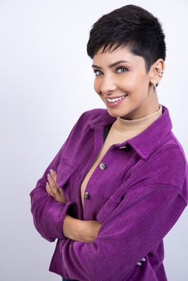mulher com olhos azuis e roupa roxa, sorrindo em fundo branco para ensaio fotográfico