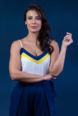 empresária empoderada vestindo conjunto azul, cabelos ondulados e postura de liderança e, fundo azul