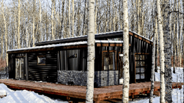 Modern prefab modular tiny home in a snowy forest setting