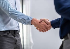 Gestión personalizada y negociación: dos personas sellando un acuerdo con un apretón de manos