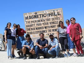 a group of people standing around a sign that says magnetic hill