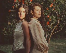 Dos mujeres lesbianas en un jardín primaveral al atardecer, simbolizando el amor LGBTQ+. Bodas gay en Madrid.