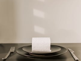 Rollo de papel higiénico, servido sobre un plato y cubiertos al lado