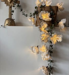 a cross on a white wall with flowers and a cross