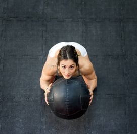 a woman doing a medicine ball exercise