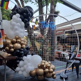 Birthday party setup at the Brunswick Hotel, white circle backdrop, neon sign and garland.