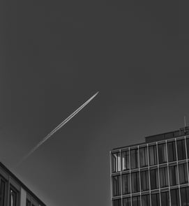 a jet plane flying over a building with a jet plane flying overhead