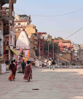 Two people walking along the ghats of Varanasi, India, by the Ganges River.