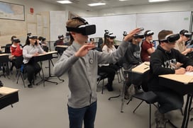 The image showcases a student wearing a VR headset, fully immersed in a virtual historical event. Th