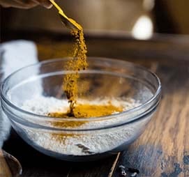 a person is pouring a mixture of spices into a bowl