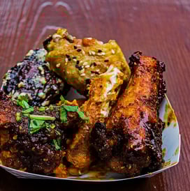 a plate of food with chicken wings and a side of corn