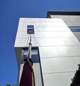Cleaning a window on a second story commercial building with a five stage filtration water pool