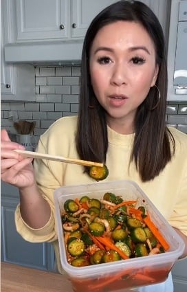 a woman holding a container with vegetables and chopsticks