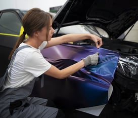 a woman worker is customizing a cars color at fix collision center