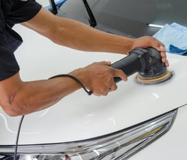 a man is buffing a white car at fix collision center