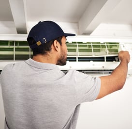 a man in a cap is fixing a air conditioner