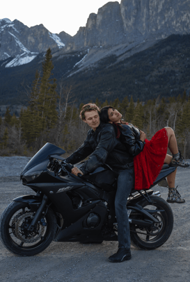 a man and woman sitting on a motorcycle during their photoshoot in Canmore