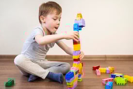 a young boy playing with blocks on the floor