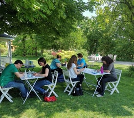Persone sedute a un tavolo che dipingono fiori con acquerelli durante un workshop creativo