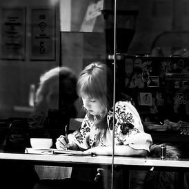 A woman writes in a cafe on Market Street, Edinburgh