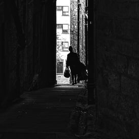 A woman, carrying shopping bags down a close off The High Street, Edinburgh