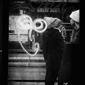 People seen through the glass of a phone box on Princes Street, Edinburgh