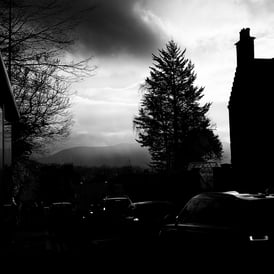 A tree and building silhouetted against a rainy looking sky on Morningside Road, Edinburgh
