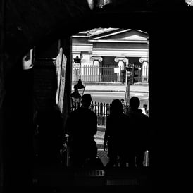 A group of people are silhouetted at the entrance Of Milne's Court, Edinburgh
