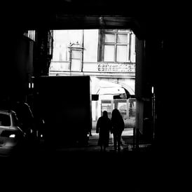 A couple, silhouetted against a sunny background, walk through Meuse Lane, Edinburgh