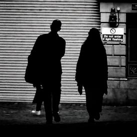 A couple, silhouetted against a bright wall in Merchant Street, Edinburgh