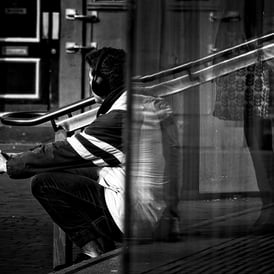 A man sits on the steps, partially distorted by the glass. The Usher Hall, Edinburgh