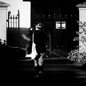 A woman, walks down a path, half in shadow in Gardener's Crescent, Edinburgh