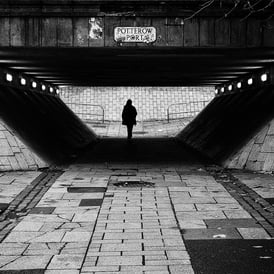 A solitary figure, in silhouette, walks through the underpass at Potterow, Edinburgh