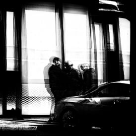 Three men, standing having a chat reflected in glass at Port Hamilton, Edinburgh