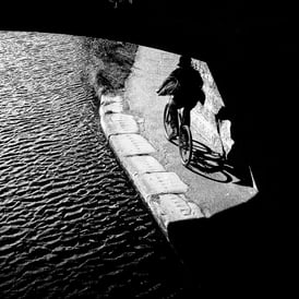 A cyclist on the canal emerges from a bridge in shadow into the light at Meggetland, Edinburgh